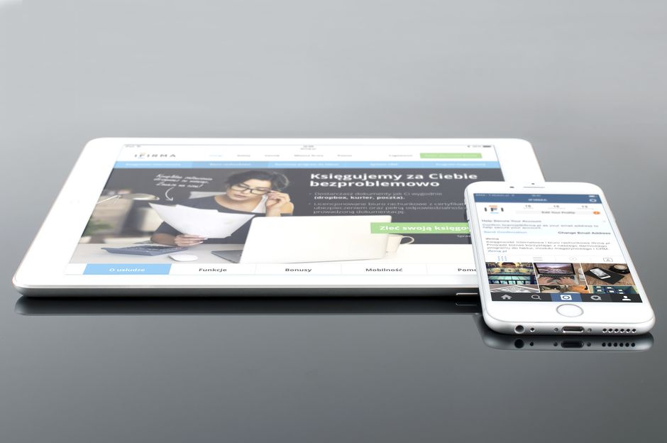 Modern tablet and smartphone displaying web content on a reflective surface, highlighting technology and connectivity.