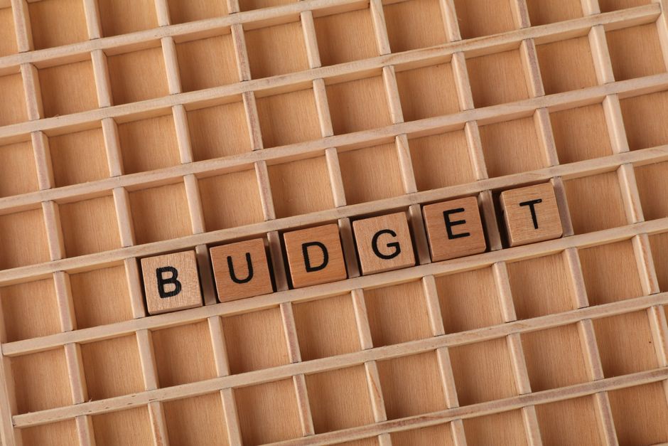 Wooden letter tiles spelling 'budget' on a wooden grid background, symbolizing finance and planning.