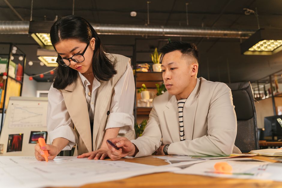 Two coworkers collaborating with documents in a stylish office environment.